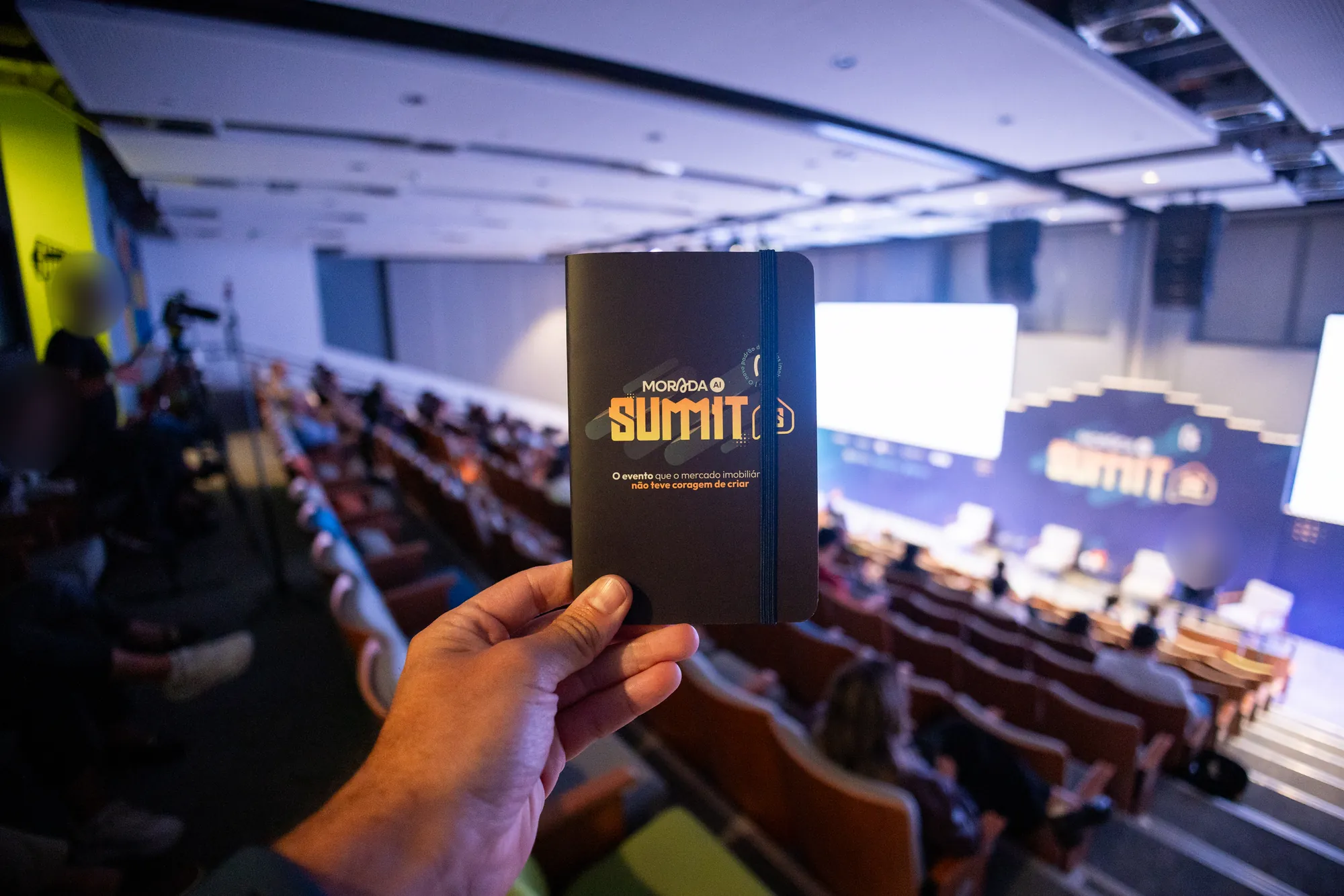 Caderno do evento com a plateia ao fundo